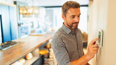 Man adjusting heat on thermostat